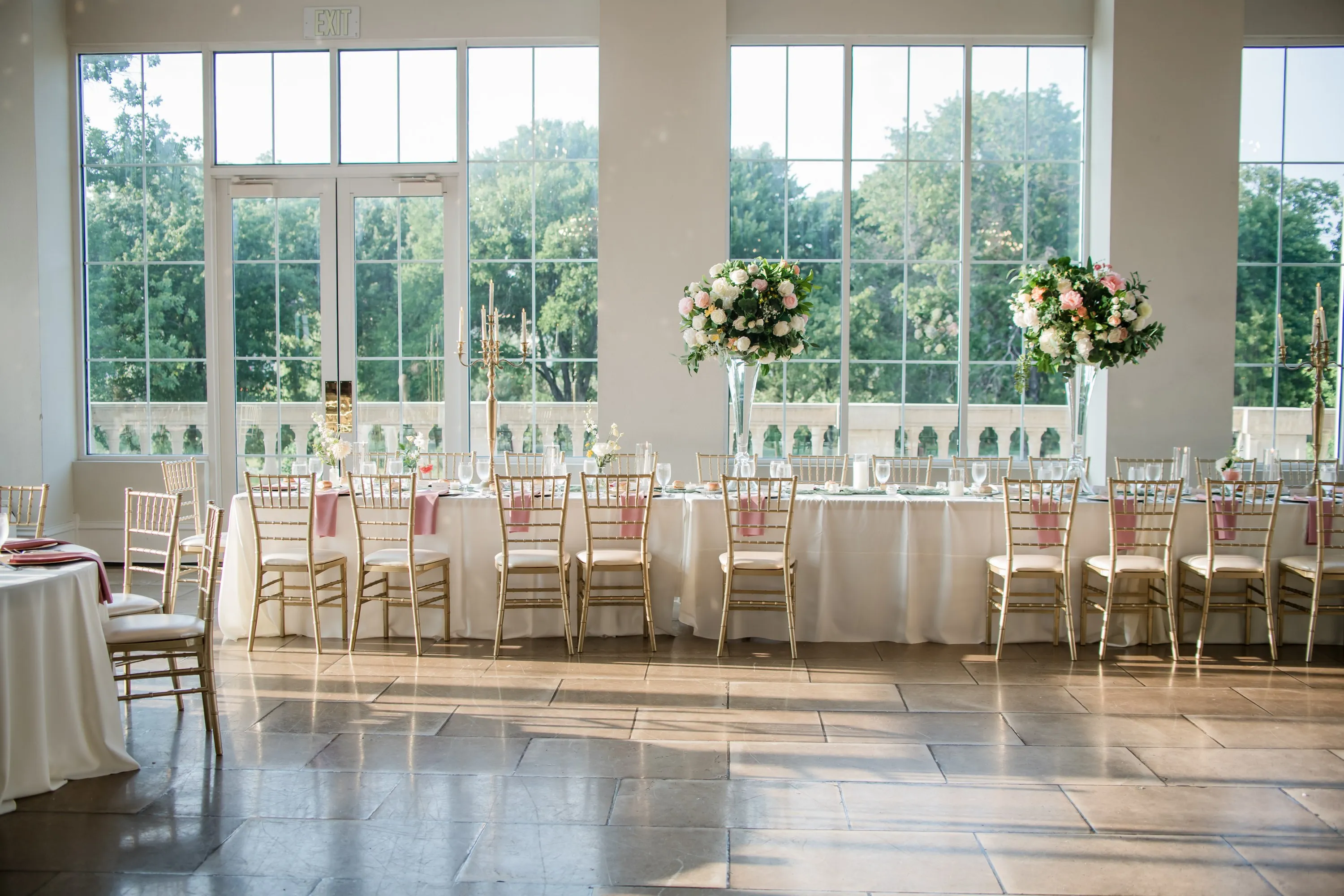 A head table dressed with tall floral arrangements and blush linens
